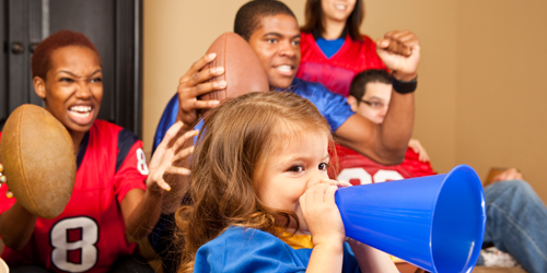 A family decked out in jerseys cheering while watching a football game.