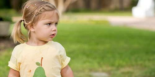 A young girl with a front braid and short ponytail playing outside.