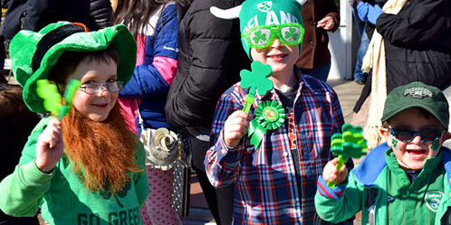 Three kids dressed up in green with festive decorations for St. Patrick's Day.